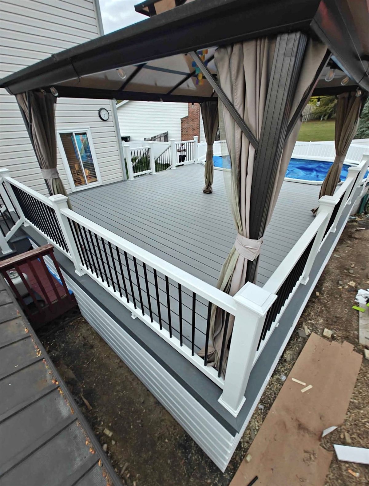 Gray composite deck with white railing and black balusters under a gazebo