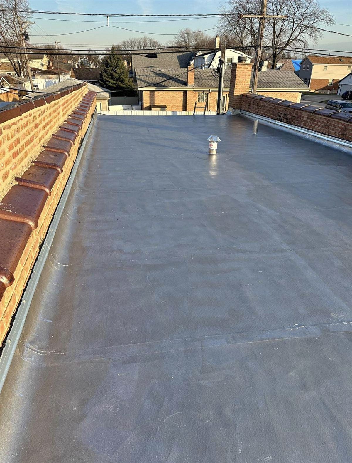 Finished flat roof with silver coating and brick parapet walls on a Chicago home