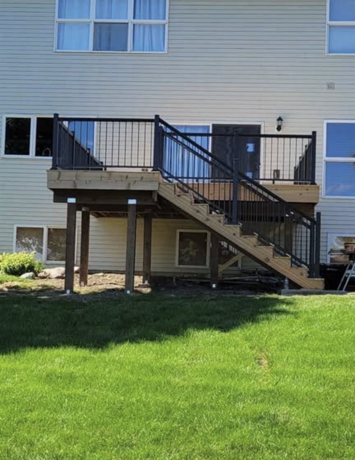 Elevated deck with black railing and a wide wood staircase to the yard
